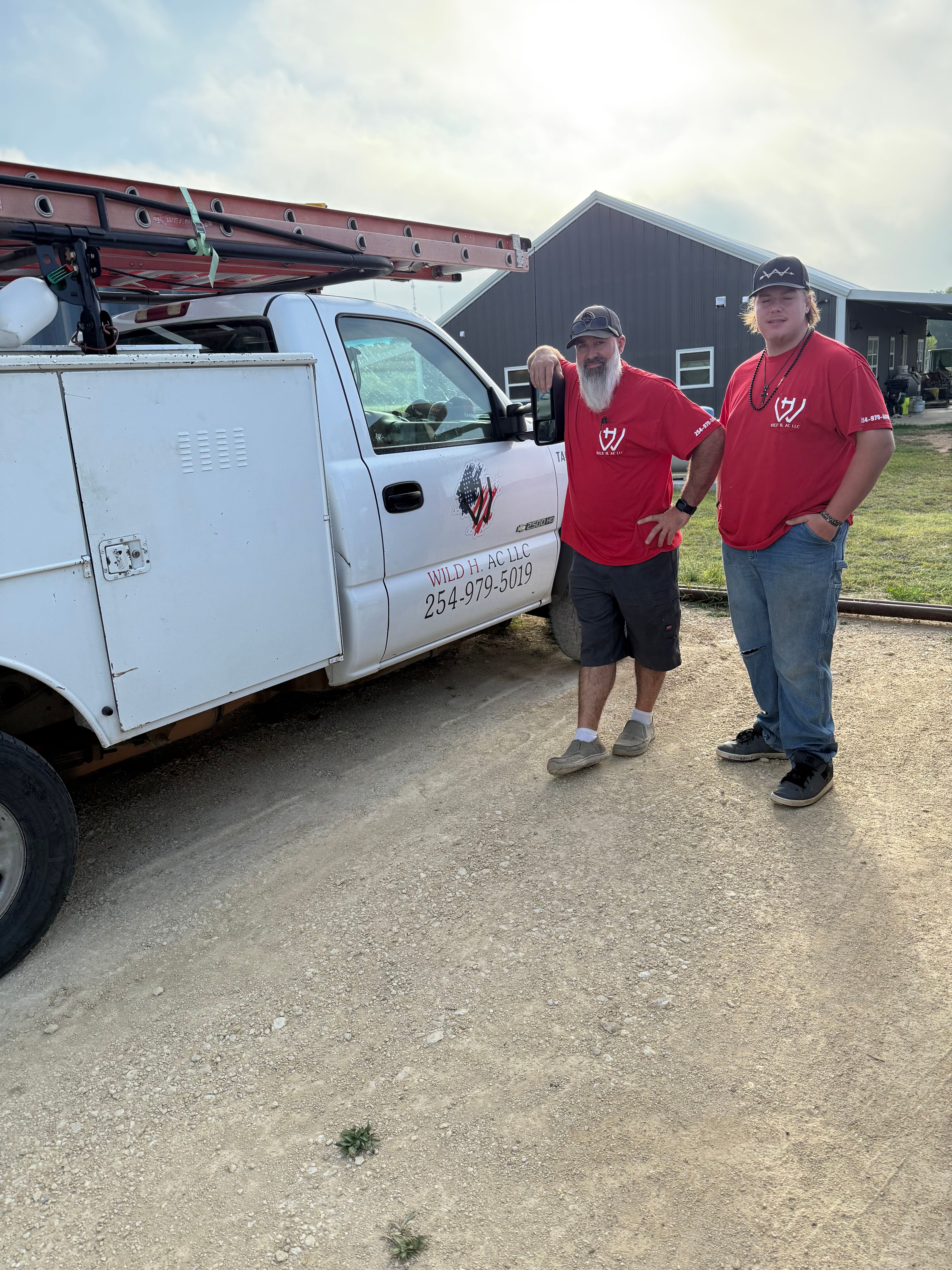 Wild H AC LLC service technician and owner in red company shirts standing beside the service truck in Dublin, TX